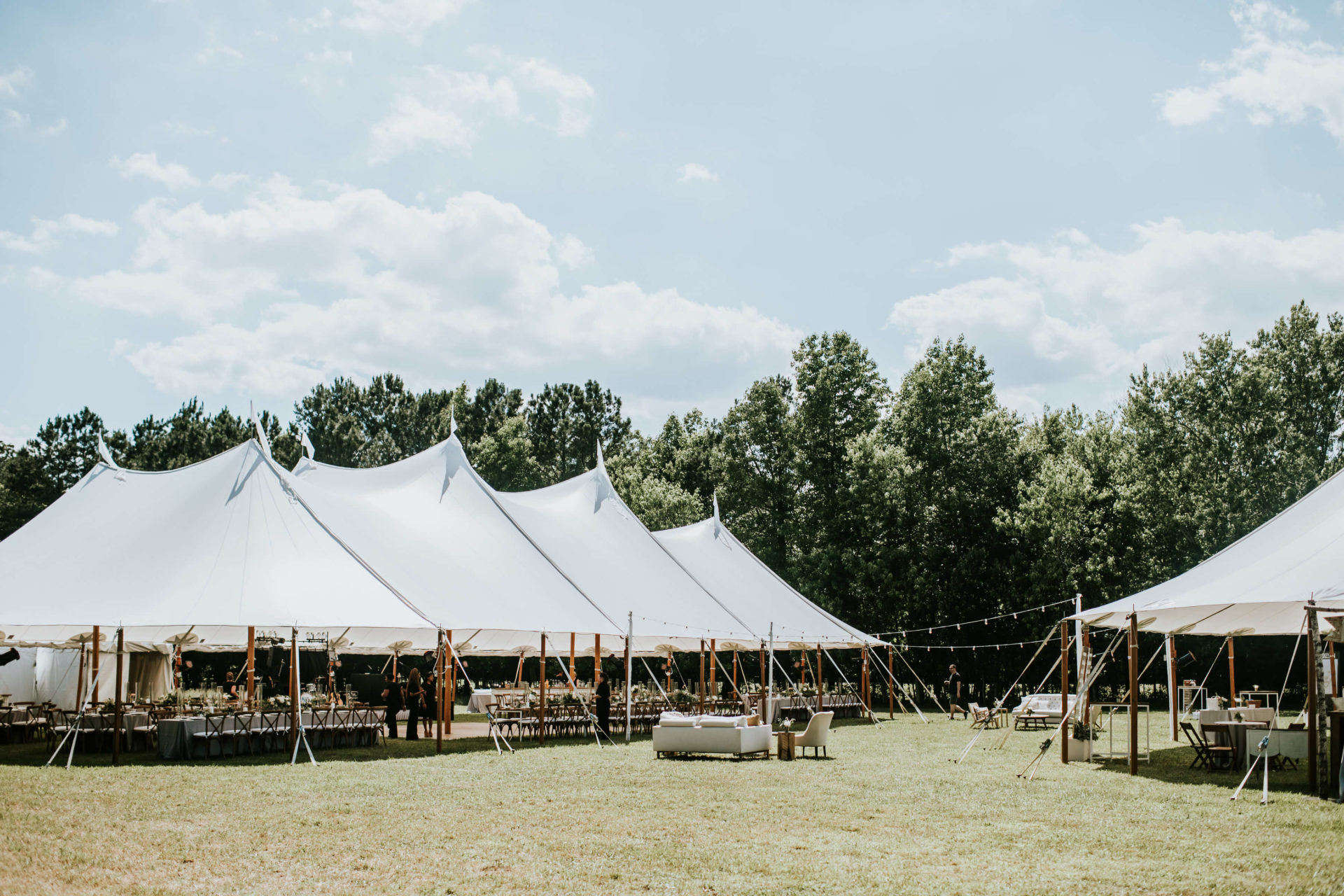 multiple white sail cloth tents in the grass