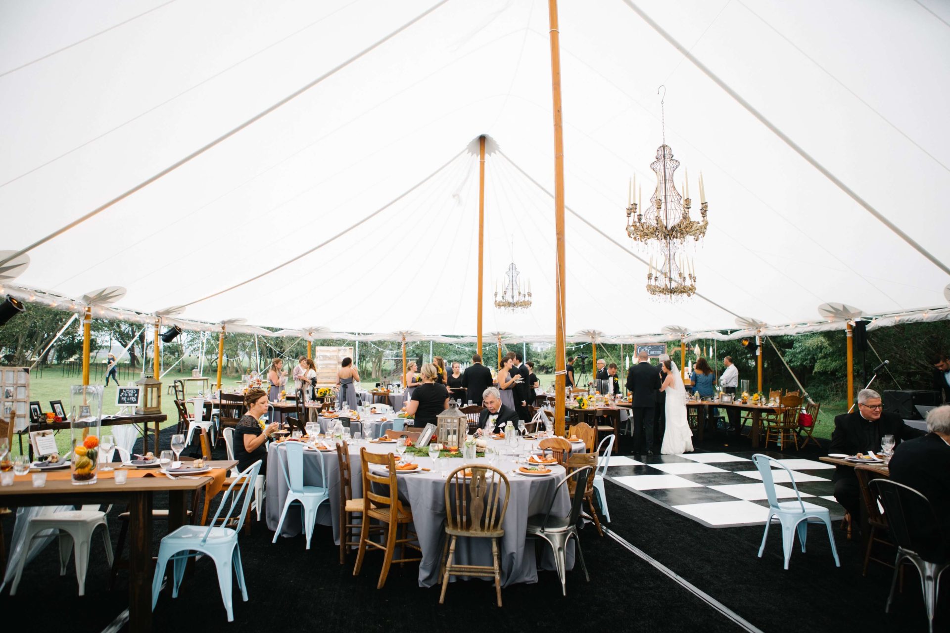 white sail cloth tent with chandeliers and black and white dance floor