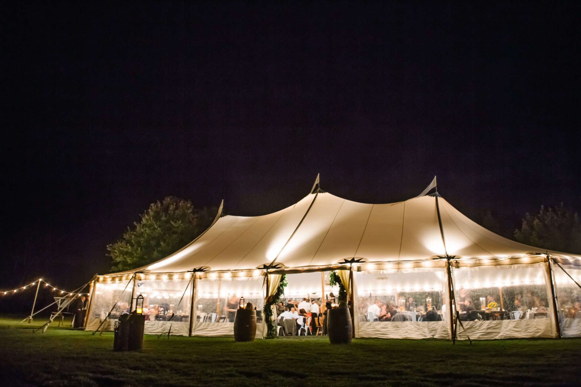 white sail cloth tent with lights inside and night sky