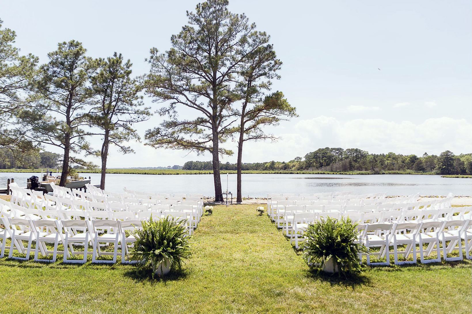 white wooden chairs in the grass beside water