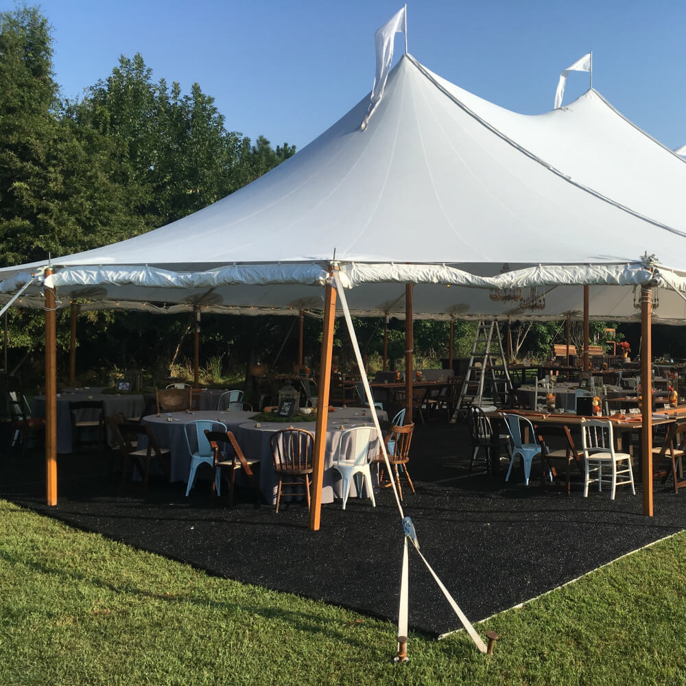 black turf under a white tent with tables and chairs underneath