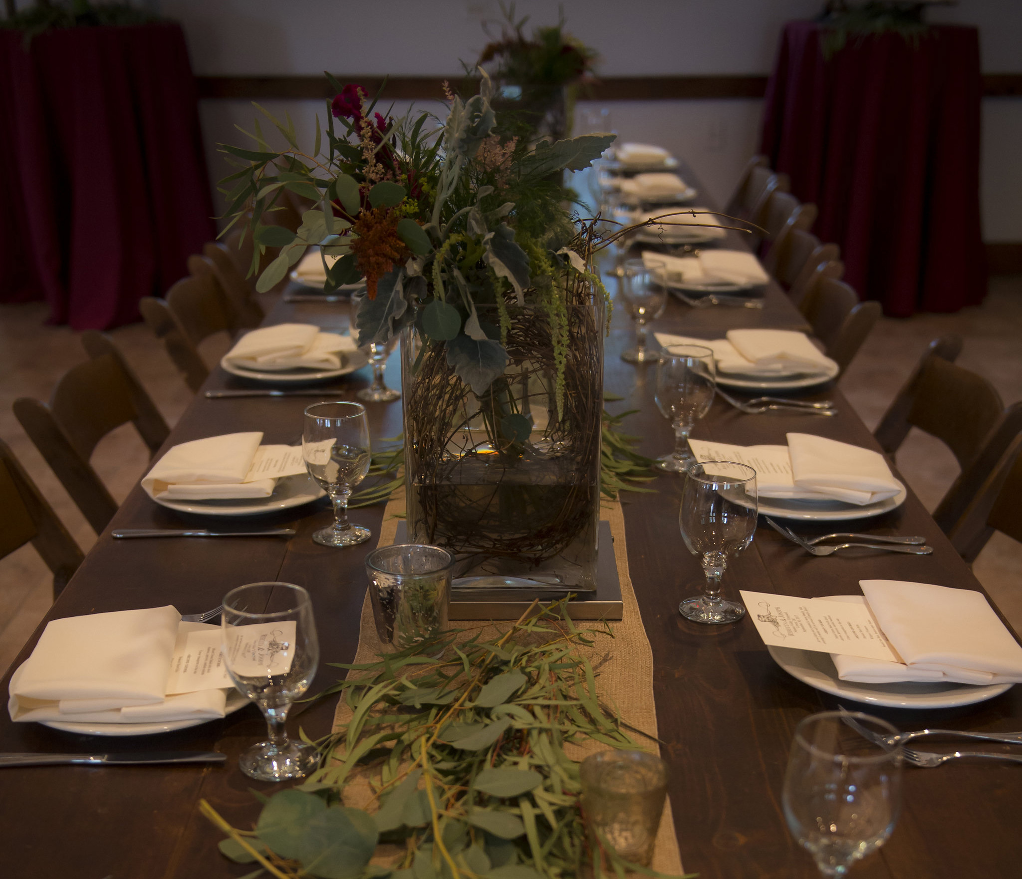wood farm table with multiple place settings and flower center piece