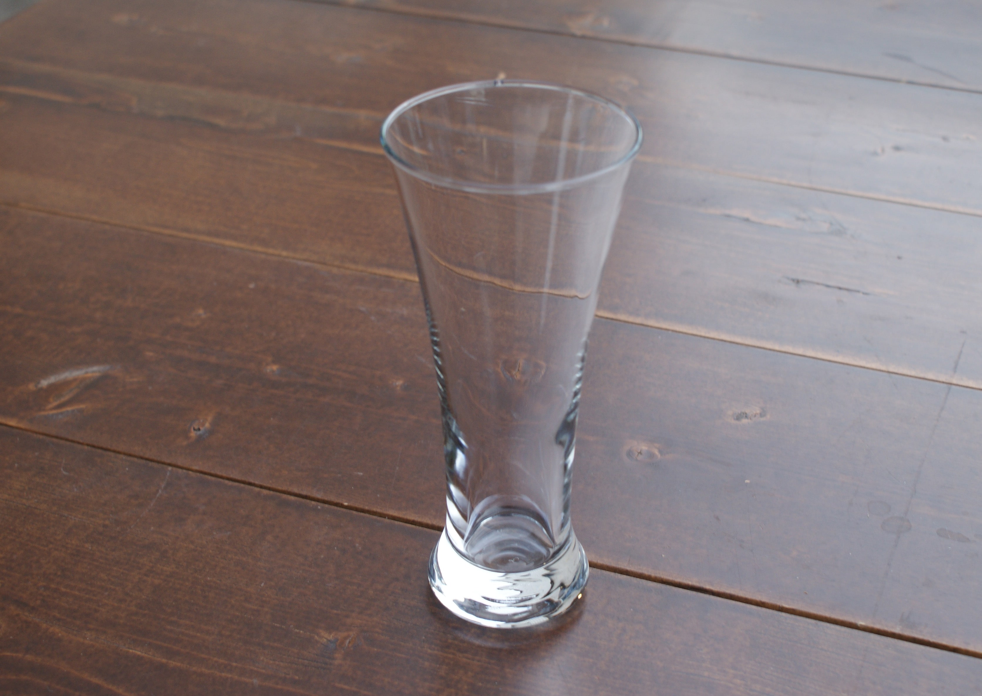 empty pilsner glass on a wood table
