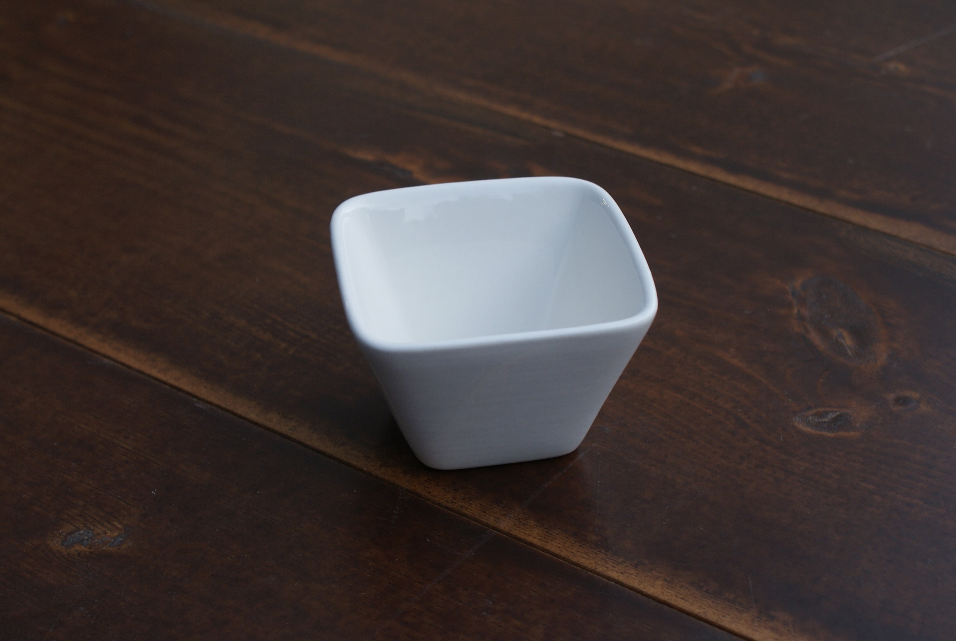 small white sauce cup on wood table