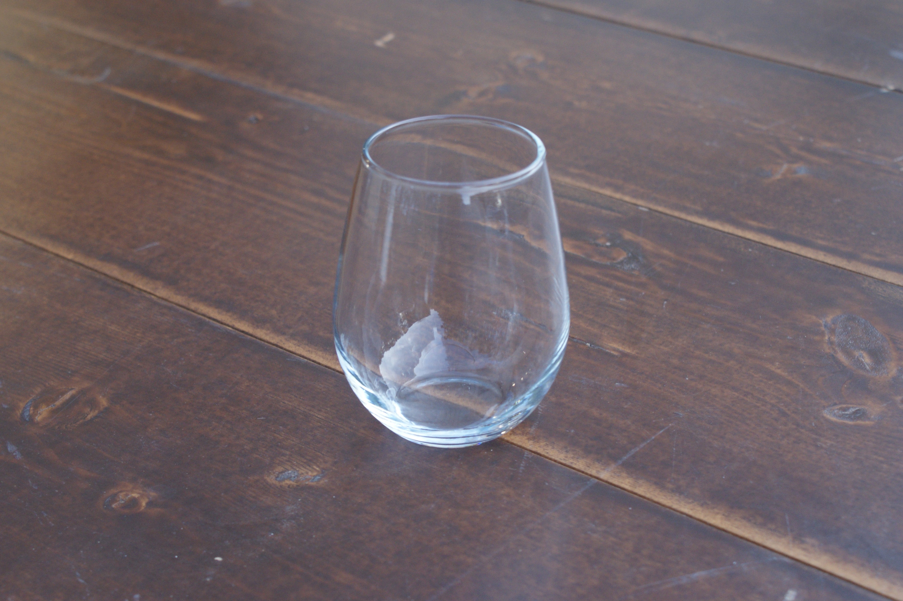 empty stemless wine glass on a wood table