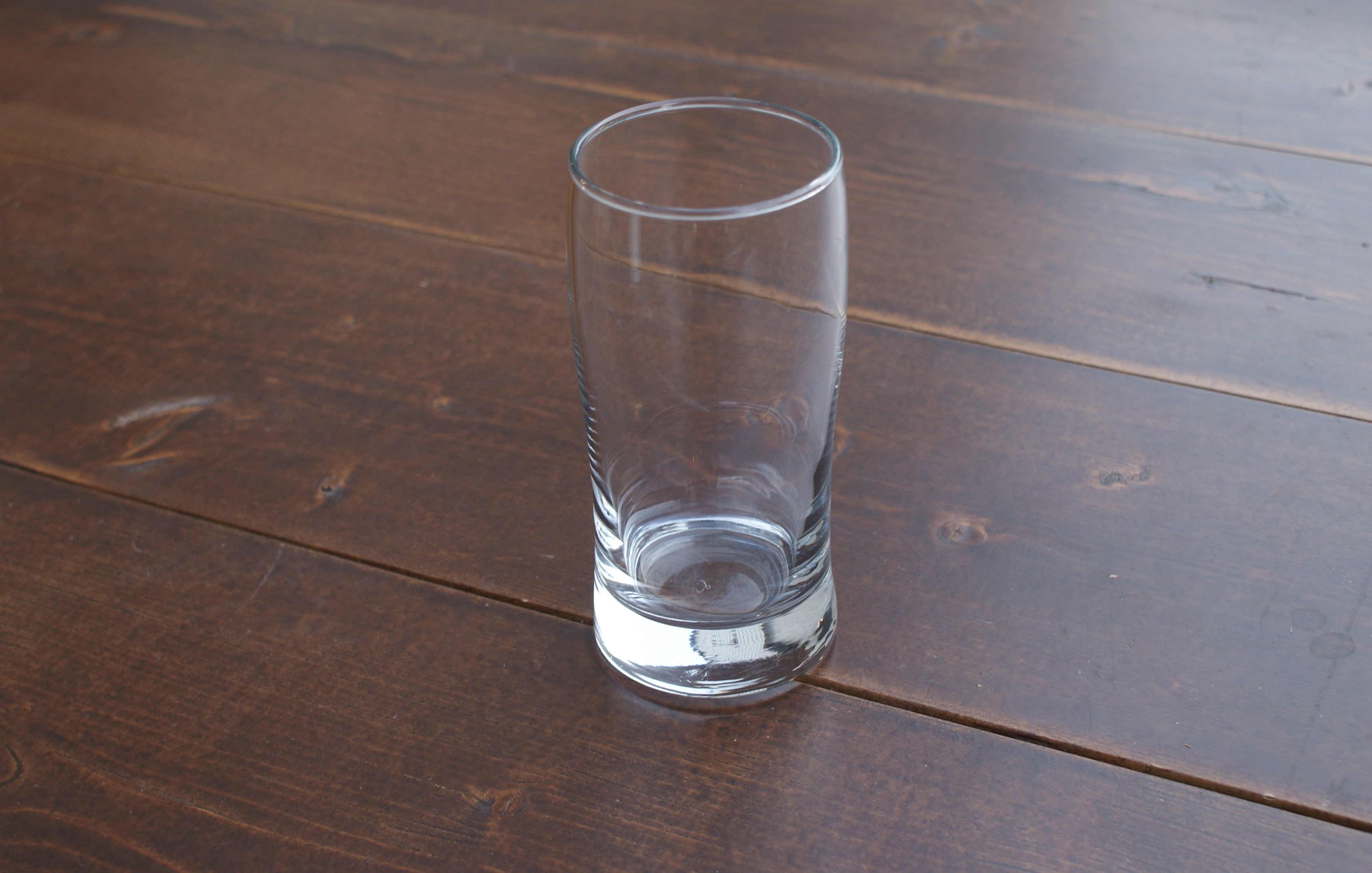 empty tall collins glass on a wood table