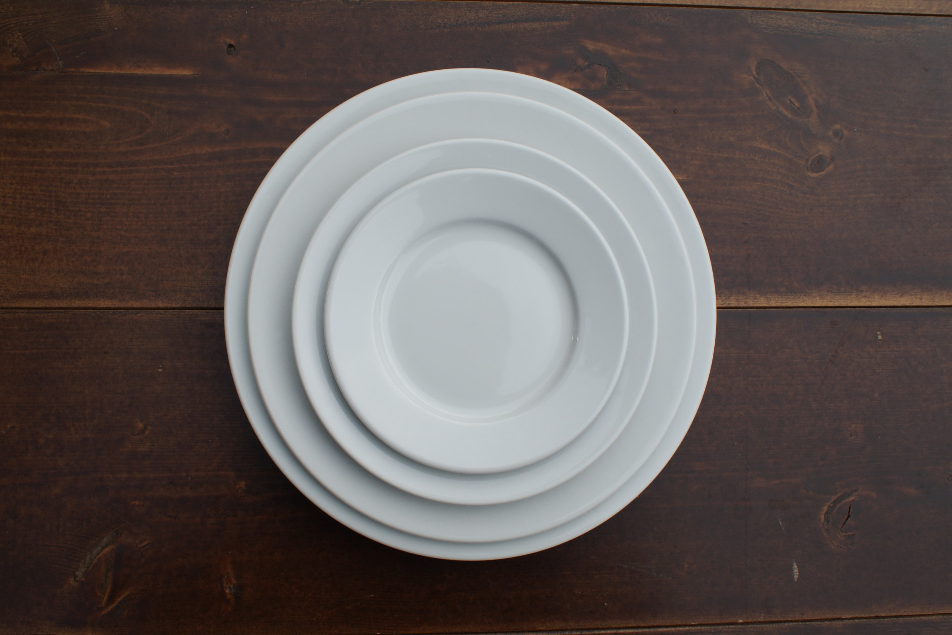 circular white plates stacked on a wood table