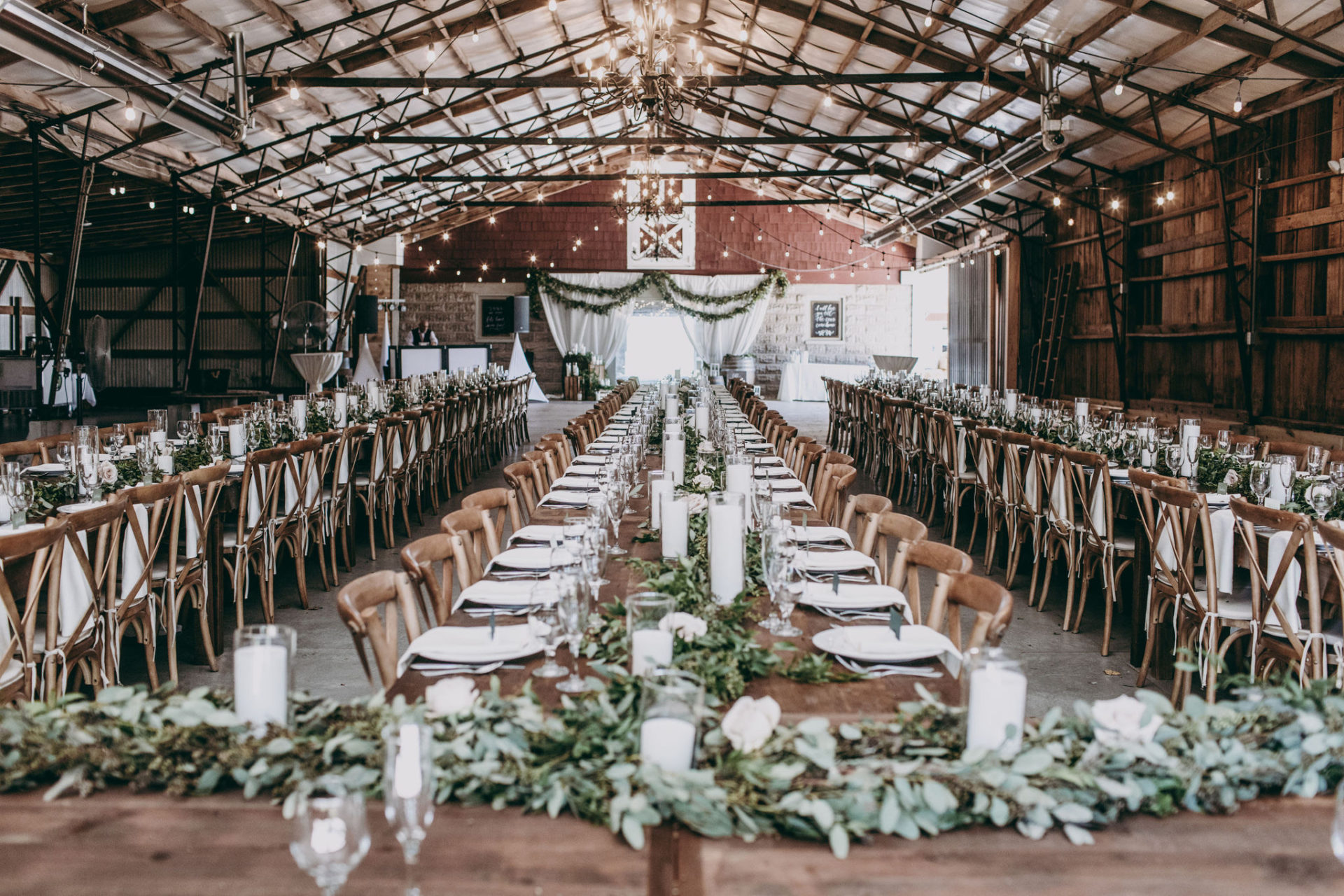 long wood farm tables inside a barn set for a wedding