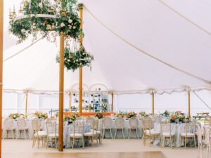 Picture of the inside of the tent with tables, chairs, and florals.