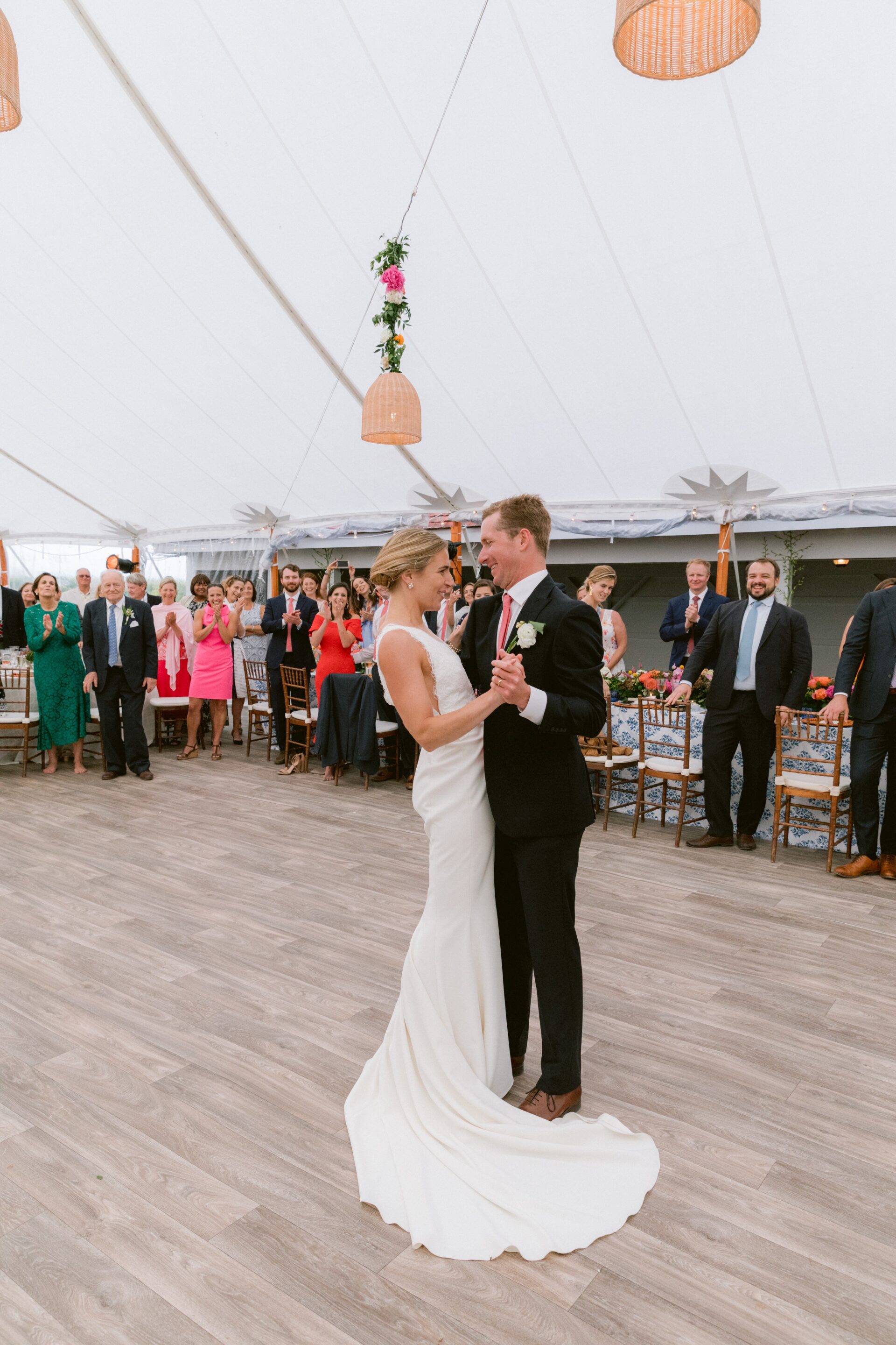 Wedding couple dancing surrounded by guests with wooden dance floor